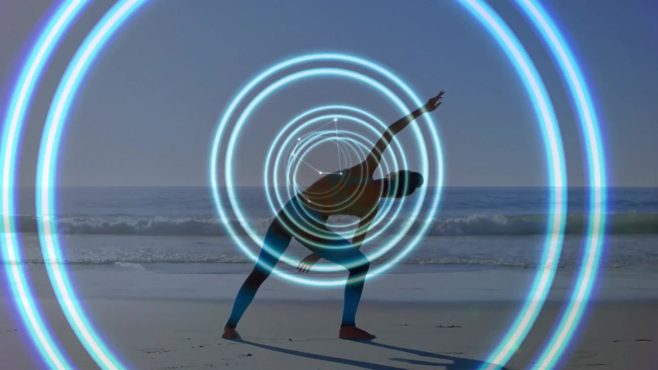 Yogini da una posizione ampia, che approfondisce un allungamento laterale sulla spiaggia, bilanciando anelli pulsanti che la centrano.