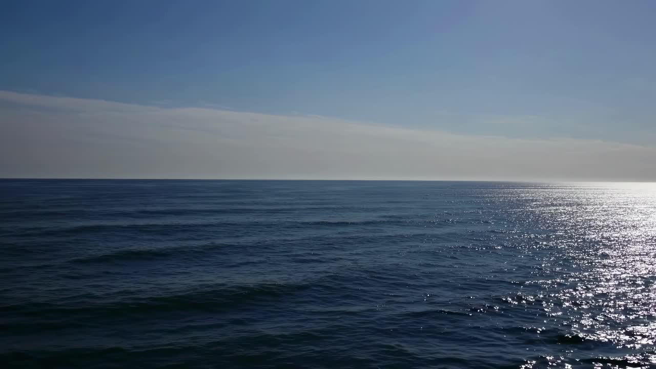 Serene ocean horizon captured from a low-angle, showcasing calm waters under a clear sky