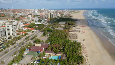 Aerial-view-of-the-beach,-palm-trees-and-the-city-around,-Praia-do-Futuro,-Ceara,-Brazil