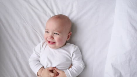 cute four month old baby wrapped into towels after shower in bed at home