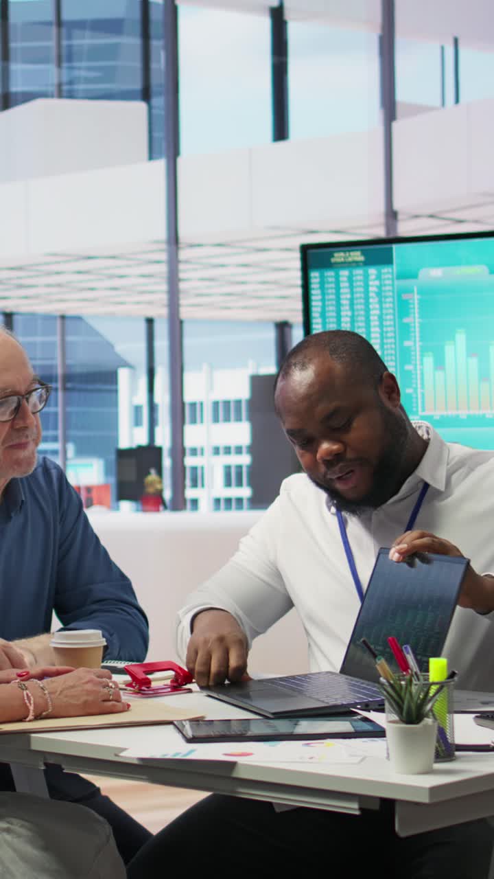Vertical Video Insurance adviser explaining retirement plans to mature people in a modern office