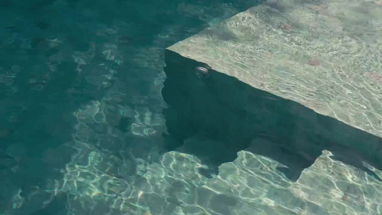 Close up Top view of pool stairs visible through clear turquoise water with sunlight shimmering across calm ripples. Clean, minimal summer scene ideal for luxury, travel, and background use.