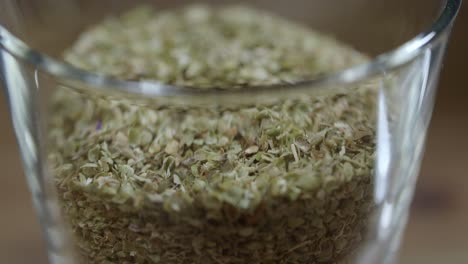 spoon dried oregano leaves into a small clear bowl, chimichurri sauce