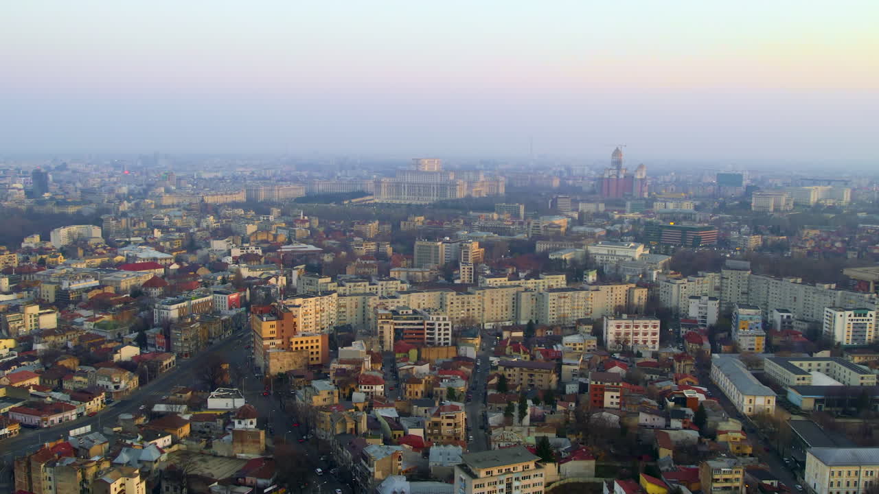 Aerial drone view of Bucharest at sunset, Romania. Palace of the Parliament in the distance, multiple buildings, moving cars