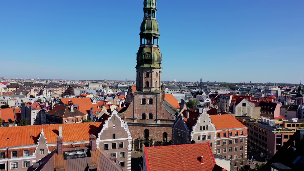 St Peters Church rises among rooftops, drone smoothly flies closer, Riga Latvia