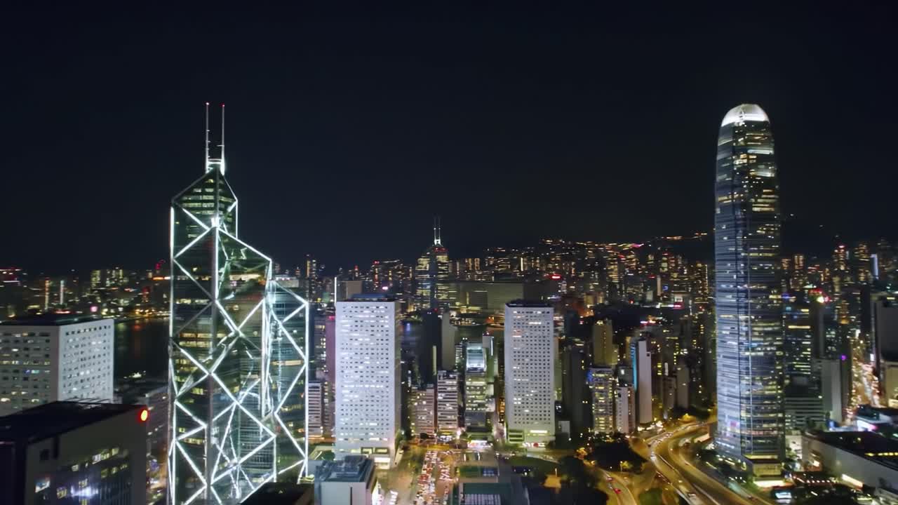 Experience the breathtaking view of Hong Kong's skyline at night. Tall skyscrapers shine brightly against a dark sky, showcasing the city's vibrant urban landscape and bustling atmosphere.