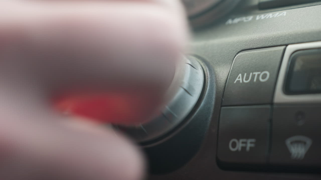 close up finger pressing off button on car air conditioning control panel with illuminated icons showing recirculation and defrost for authentic cabin interior detail softly under ambient light