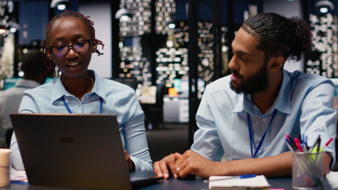 Diverse team of businesspeople at desk using laptop evaluating metrics