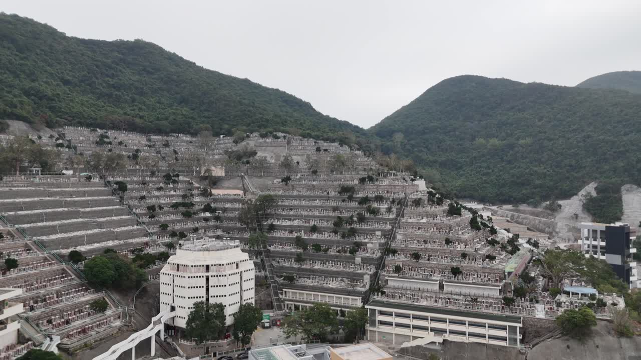 Vista aérea con dron del Cementerio Pok Fu Lam en Hong Kong, capturando tumbas en la ladera, vegetación exuberante y el diseño panorámico del cementerio urbano desde arriba.