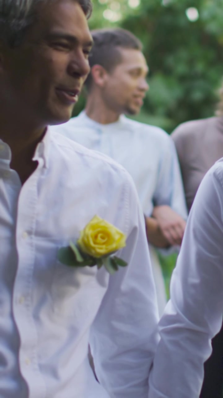 Video verticale: Ospite che arriva, uomo con papillon bianco che si protende e si lega a una rosa gialla in giardino.
