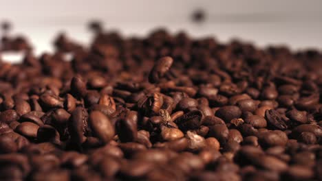 slow motion footage of roasted coffee beans falling on a small pile of more beans.