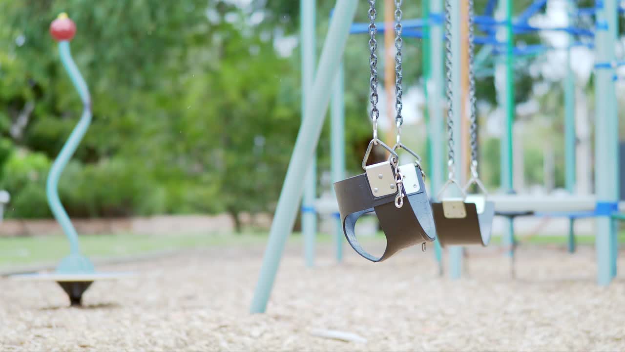 Young kids swing waving in the child playground with the little raining and weak wind day