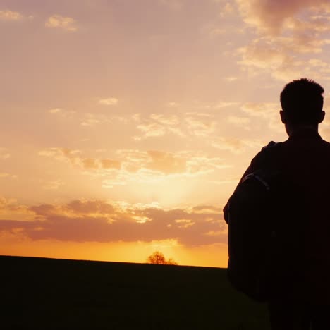 un adolescente con una mochila espera el sol y el horizonte