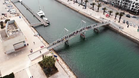 crowd of people crossing a pedestrian bridge at marina de lagos, algarve