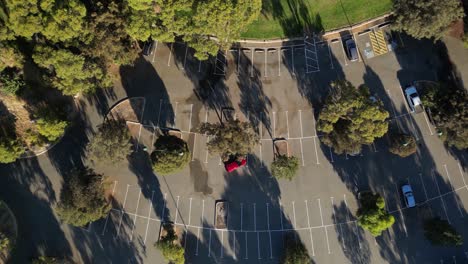 Toma-Aérea-De-Arriba-Hacia-Abajo-De-Los-Autos-De-Estacionamiento-En-El-Estacionamiento-En-La-Ciudad-De-Perth-Cerca-De-La-Playa-Y-El-Océano-Al-Atardecer