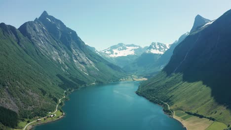 vista aérea panorámica de un fiordo azul profundo rodeado de altas montañas y verdes valles en noruega