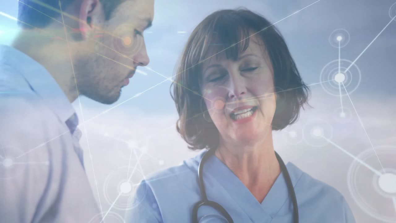 Doctora girándose hacia su colega explicando líneas de datos y tocando una tableta durante una consulta médica.