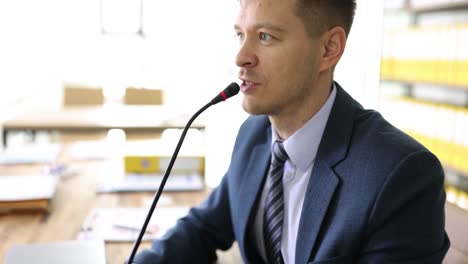 man speaking into a microphone at a conference or meeting