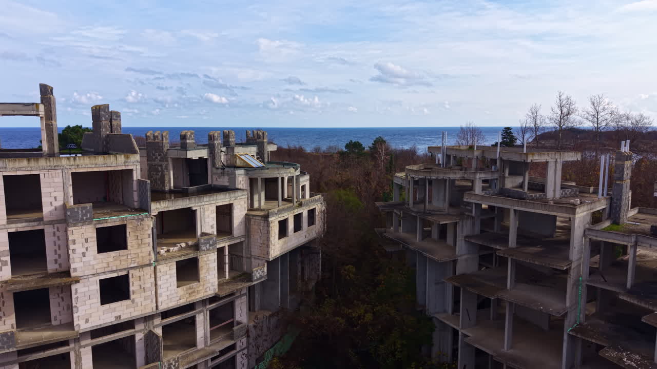 Esplorazione di strutture dimenticate in riva al mare mentre la natura si riappropria di edifici abbandonati sotto un cielo nuvoloso