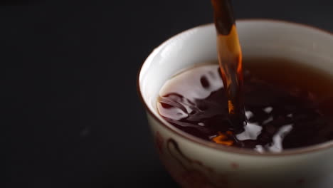 pouring tea into a small porcelain cup