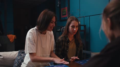 2 chicas amigas ganan el juego de mesa y el high five entre sí porque ganaron en la noche en una habitación acogedora
