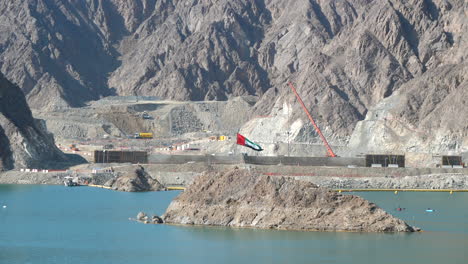 bandera de los emiratos árabes unidos ondeando en el sitio de construcción y kayaks en el lago de la presa de hatta