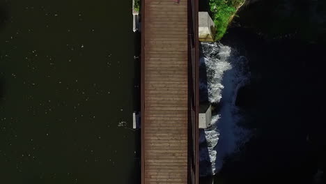 top view of a woman jogging on wooden pathway above dam spillways with flowing water