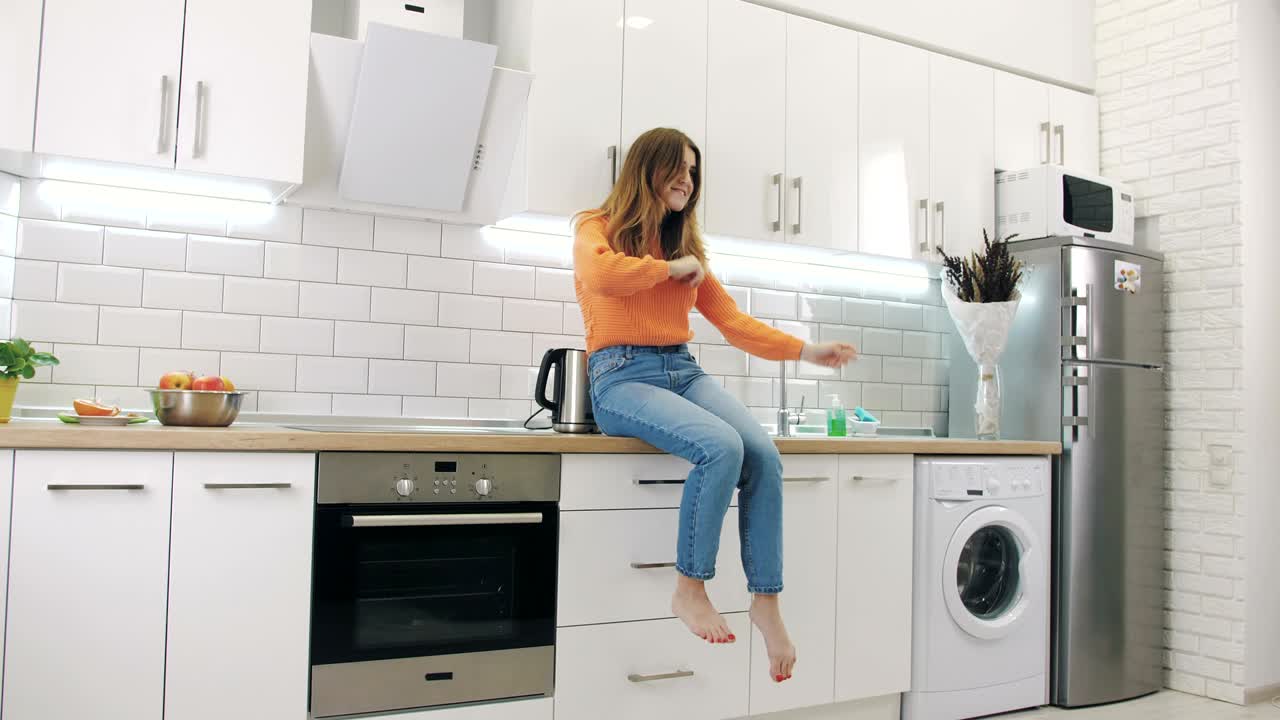Giovane donna felice che balla in cucina e si diverte