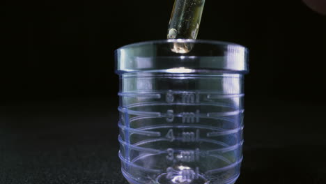 drops of experimental vaccine fall down into plastic flask