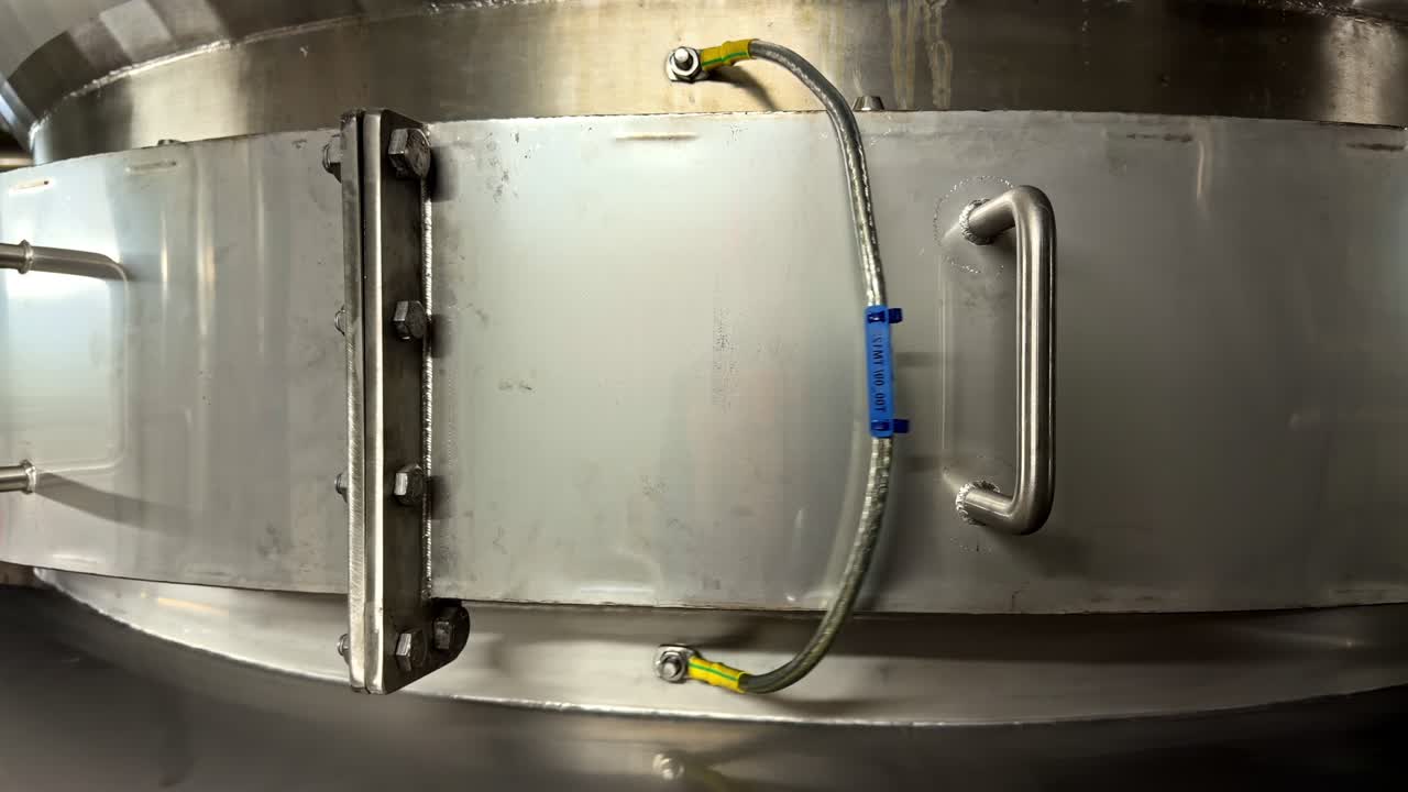 A metal clamp with a blue tag secures a pipe in an industrial setting. The scene highlights precision engineering. Suitable for manufacturing or engineering content