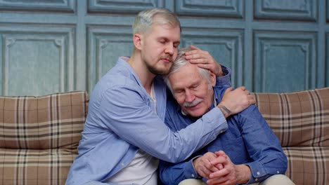 joven pidiendo disculpas a ofendido estresado anciano padre mayor sentados juntos en el sofá