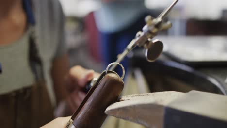 biracial female worker shaping jewellery with saw in studio in slow motion