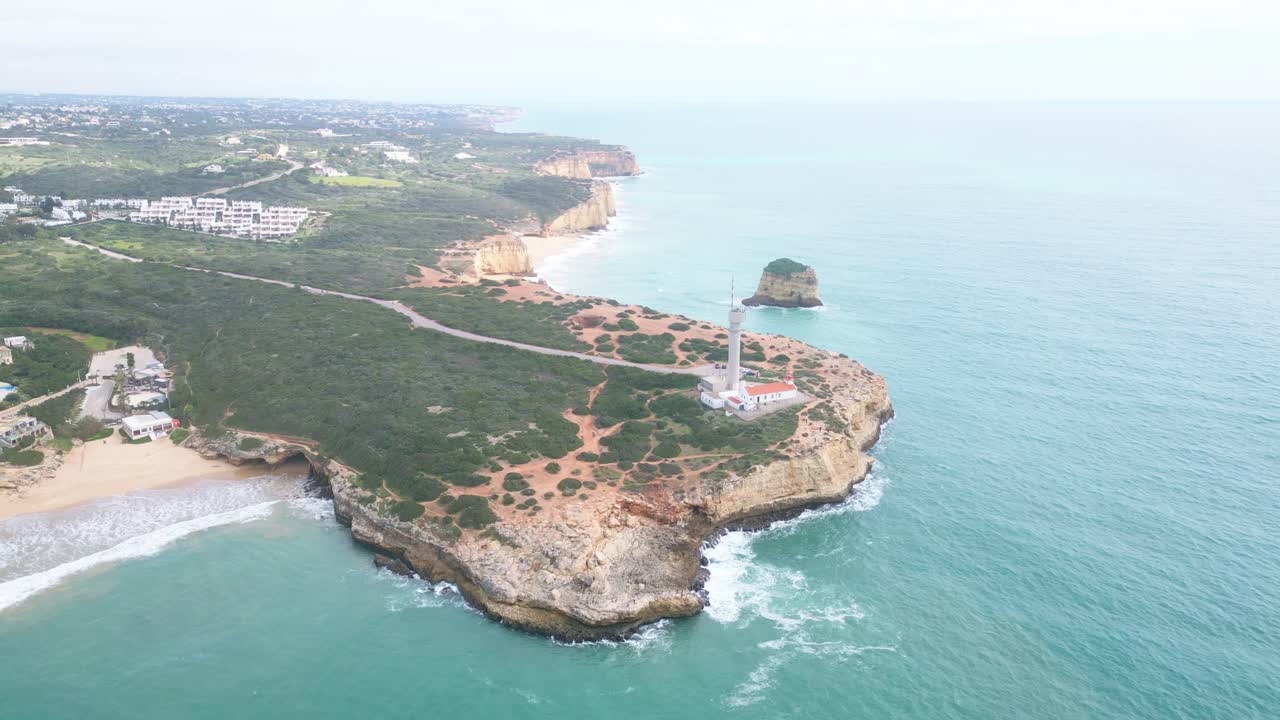 Cliffside lighthouse by turquoise sea, Ferragudo Algarve coast aerial view