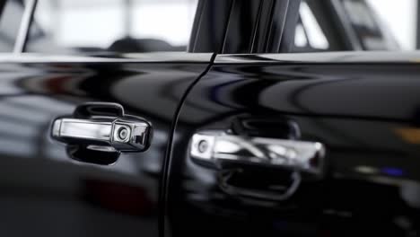 close-up view of a glossy black vehicle door with distinctive handles and clear reflections, highlighting the modern design aesthetics in automotive artistry