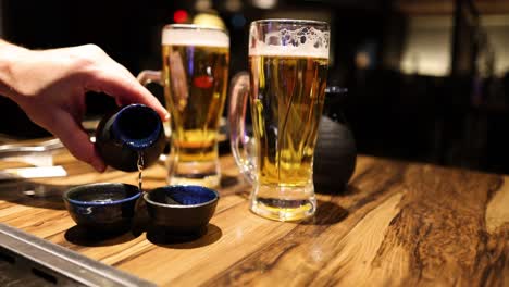 sequential sake pouring next to beer glasses