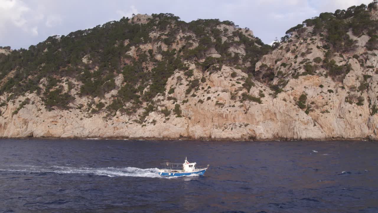 volando sobre un pequeño barco de pesca en el océano cerca de la costa de mallorca, aéreo