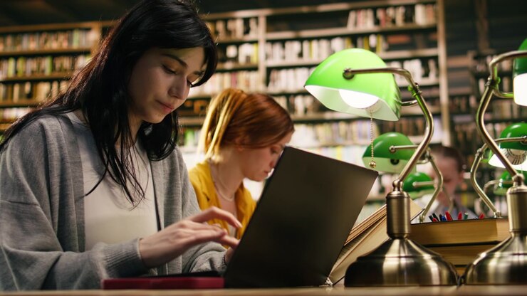 Giovane studente distratto da una notifica del cellulare mentre usa il portatile.