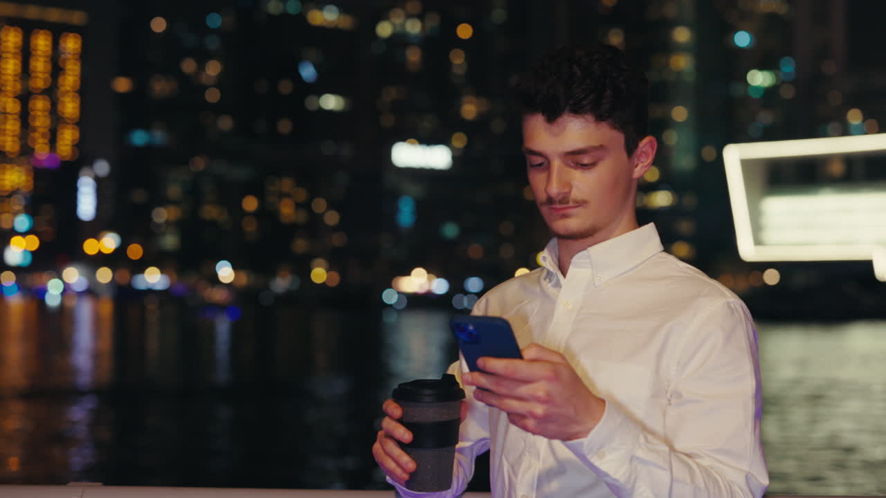 Man using smartphone in city at night