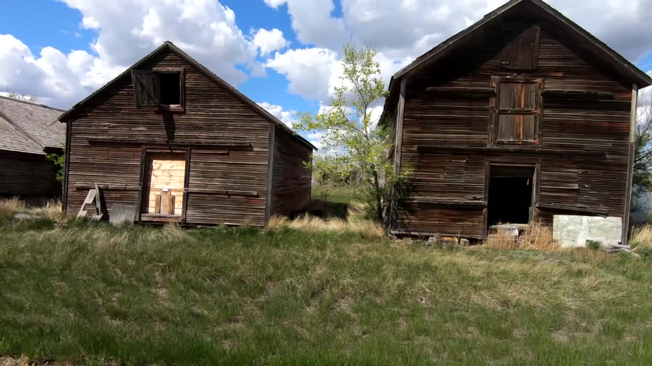 un viejo granero abandonado en tierras de cultivo durante un buen día con nubes en el cielo