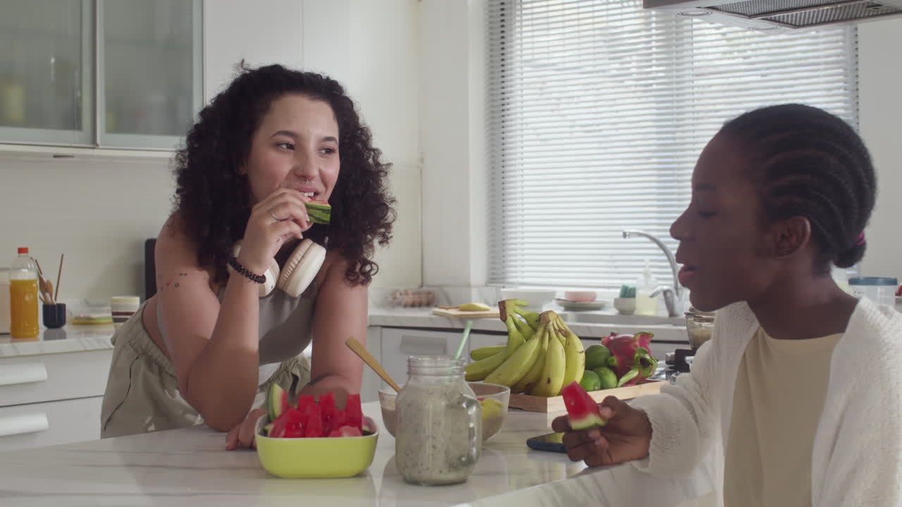 Young Woman Eating Watermelon and Communicating with Friend
