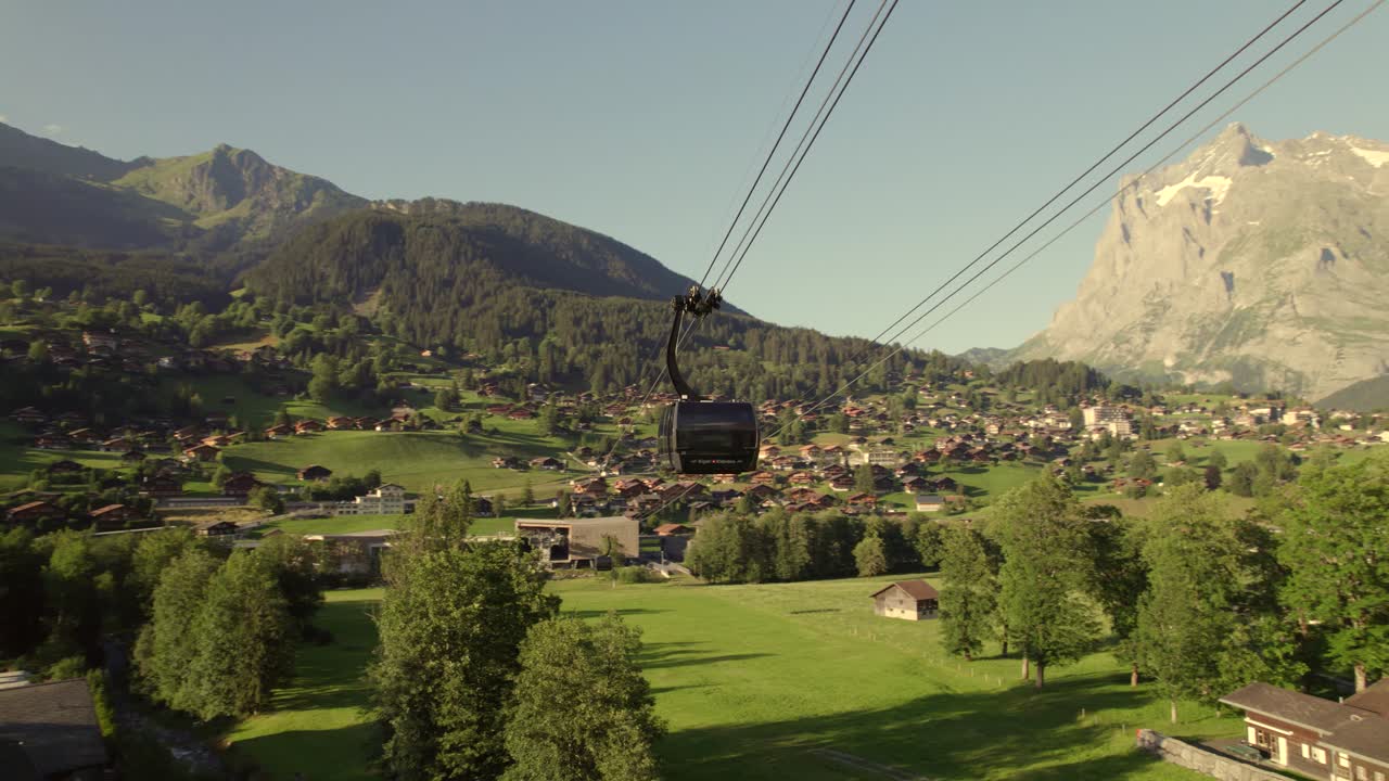 órbita de una cabina del sistema de tricable eiger express en grindelwald con vistas a la estación terminal, el pueblo de grindelwald y las montañas