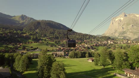 orbit of a cabin of tricable car system eiger express in grindelwald with views of terminal station, grindelwald village and mountains