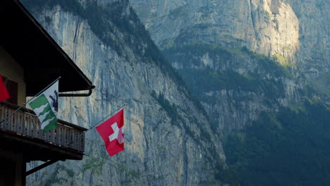 pared de roca de lauterbrunnen y balcón de un chalet de madera en un pueblo de montaña con bandera suiza