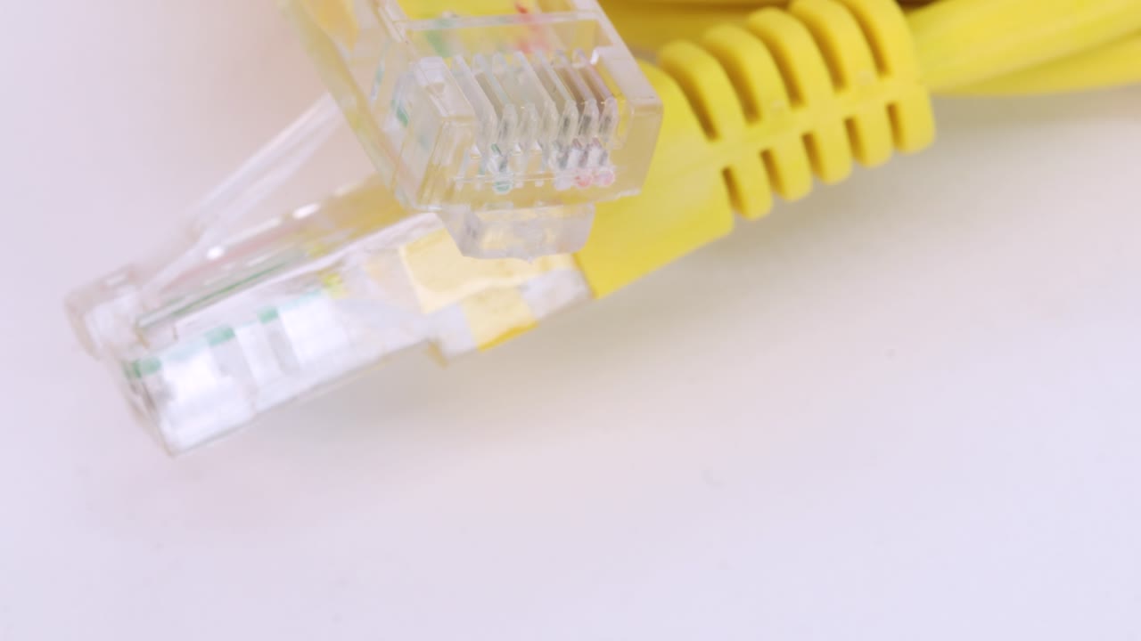 Ethernet yellow cable rotating on white surface, close up view from above in 4k