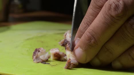 hombre hábil pescador manos cortar pulpo en la mesa verde, el hombre prepara la comida en casa