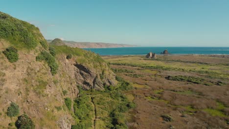 Flug-über-Die-Felsige-Küstenlandschaft-Neuseelands-In-Richtung-Vulkanischer-Whatipu-Strand-Mit-Schwarzem-Sand