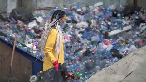 Mujer-Elegante-Con-Chaqueta-Amarilla,-Gafas-Protectoras-Y-Guantes-Clasificando-Botellas-De-Plástico-De-Bolsas-Negras