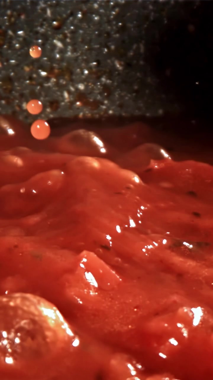 Primo piano di salsa di pomodoro rossa che sobbolle e viene mescolata in una padella