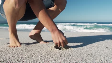 hombre agachado en la playa