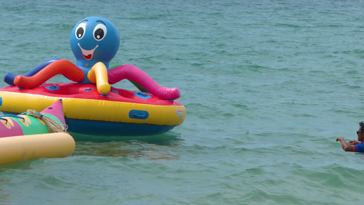 Colorful inflatable water sports equipment floats on the ocean surface under bright natural daylight